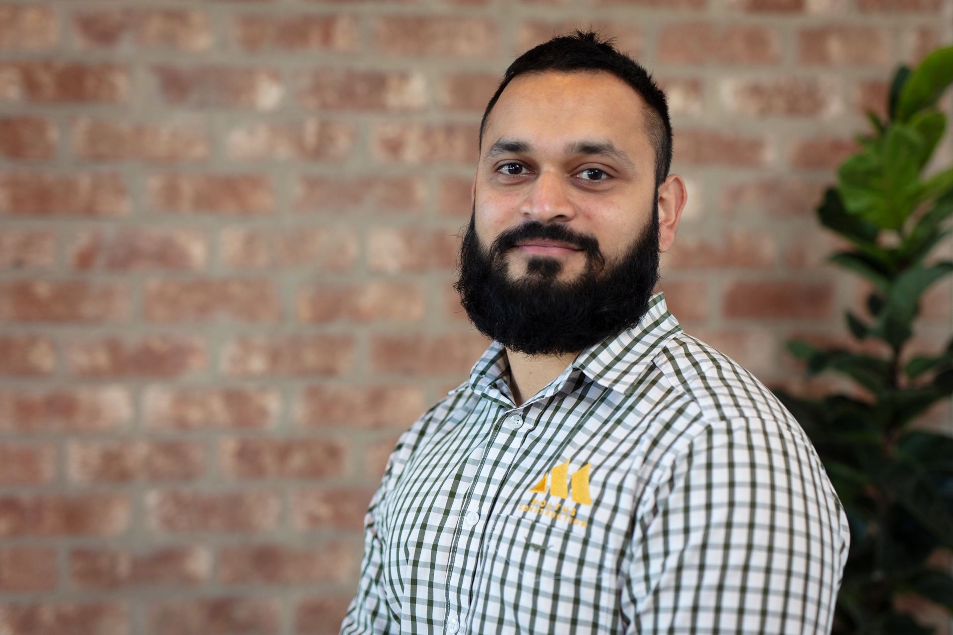 A Man With a Beard is Standing in Front of a Brick Wall — Moltus Construction in Braddon,  ACT