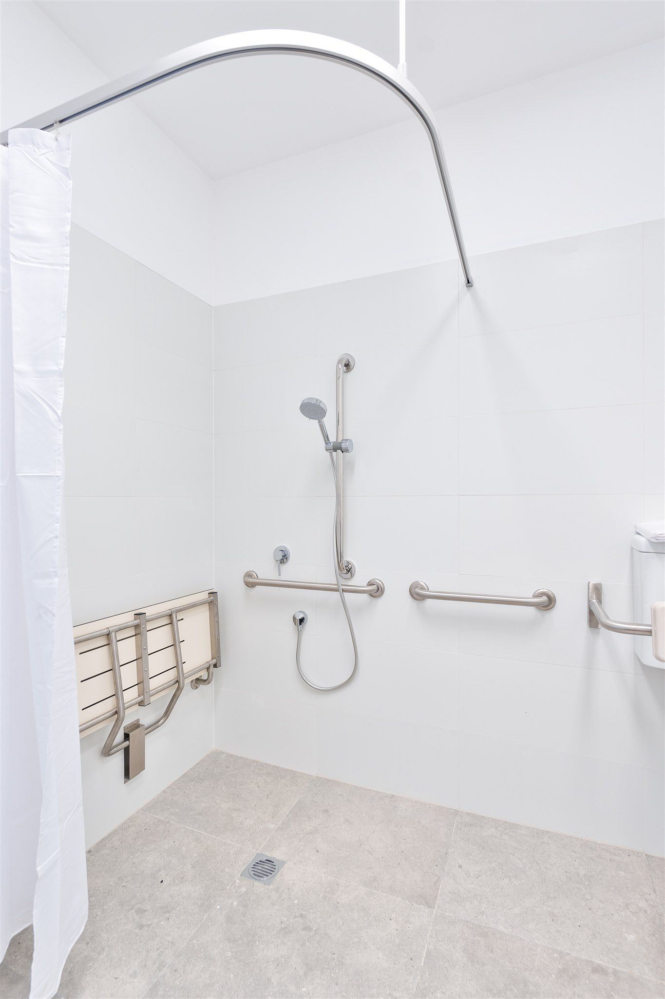 A Handicapped Shower With a White Curtain and Stainless Steel Handles — Moltus Construction in Braddon,  ACT
