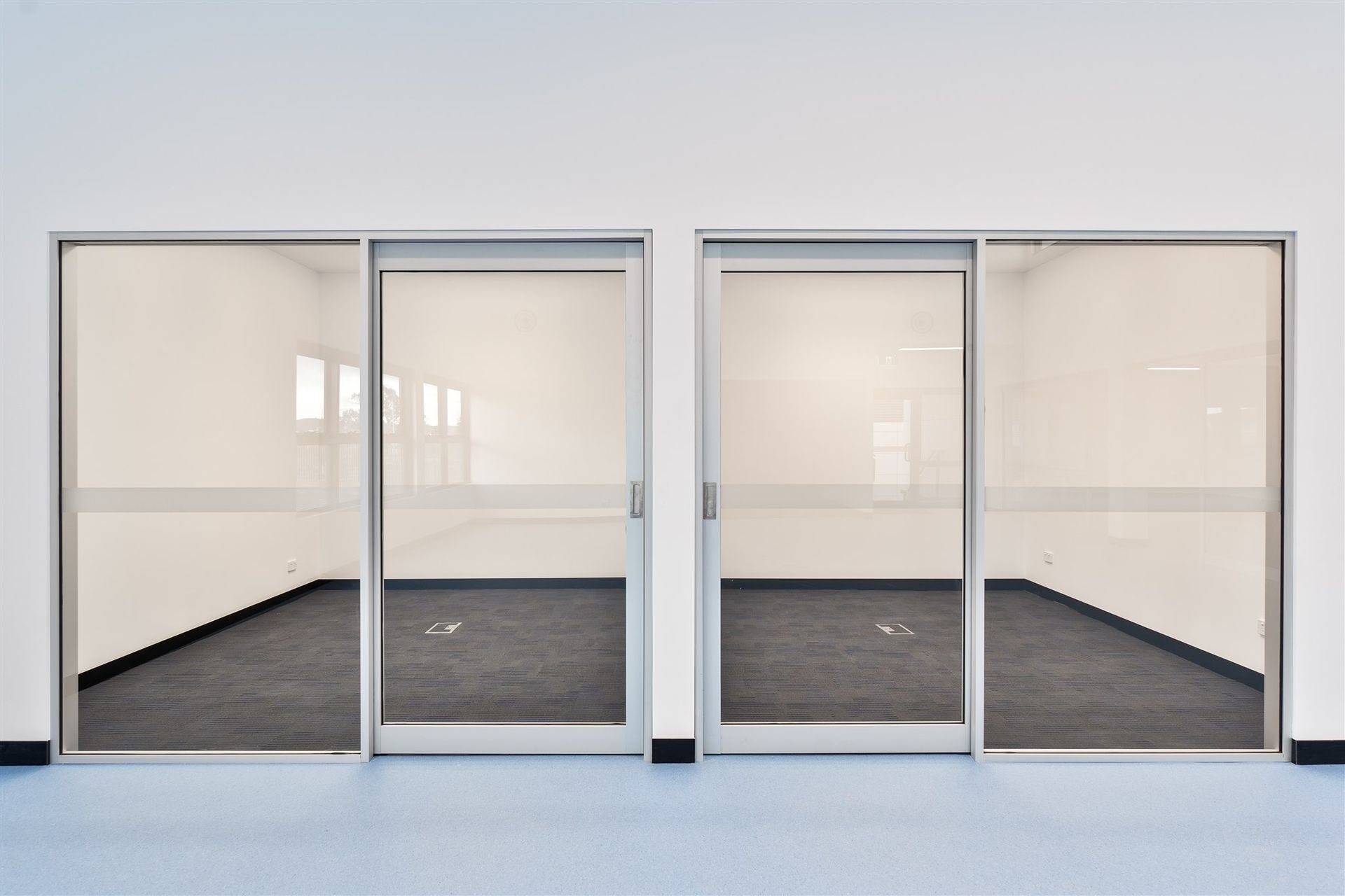 An Empty Room With Sliding Glass Doors and a White Wall — Moltus Construction in Braddon,  ACT