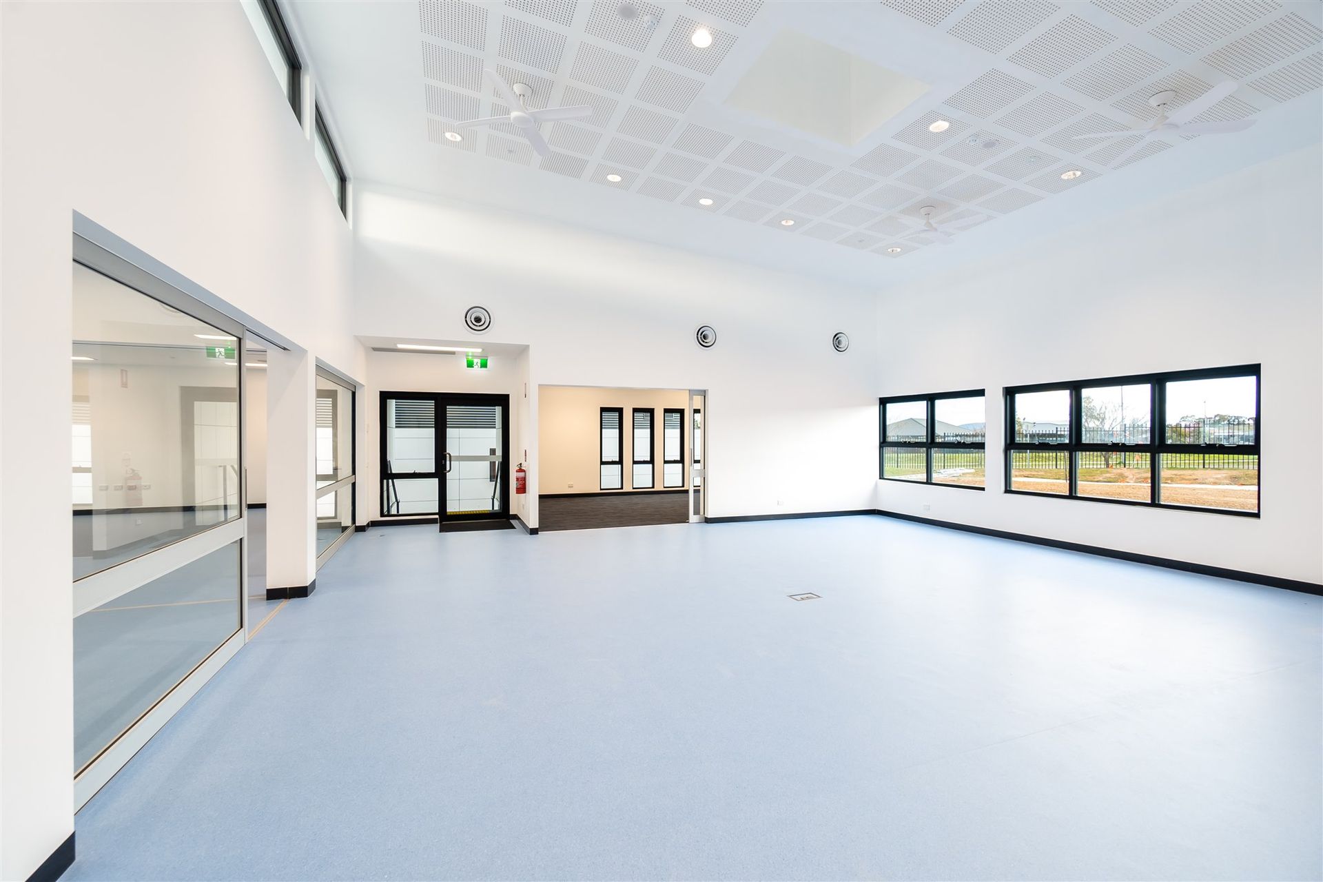 A Large Empty Room With Blue Floors and White Walls — Moltus Construction in Braddon,  ACT