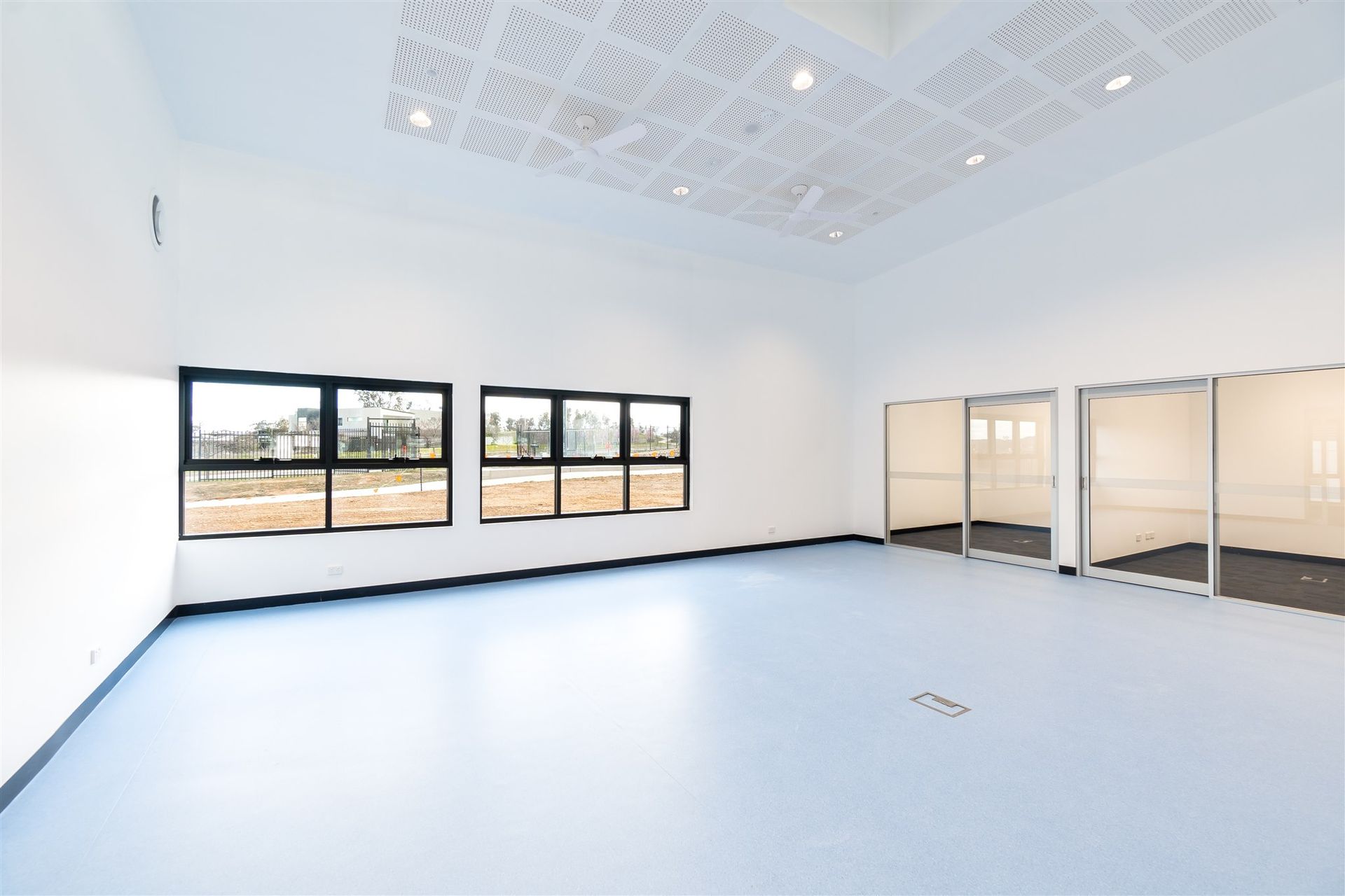 An Empty Room With a Blue Floor and a Lot of Windows — Moltus Construction in Braddon,  ACT