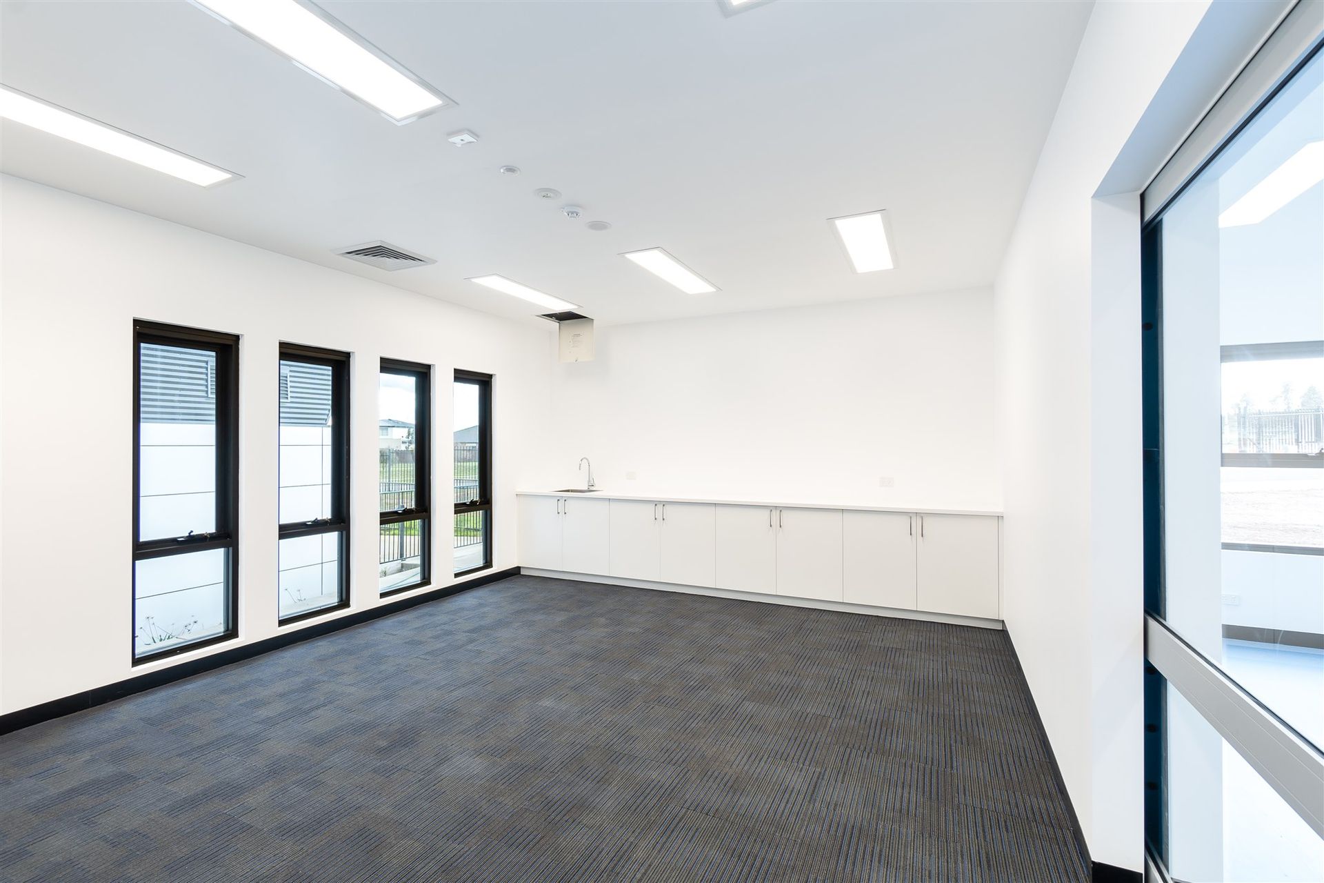 An Empty Room With a Lot of Windows and a Black Carpet — Moltus Construction in Braddon,  ACT