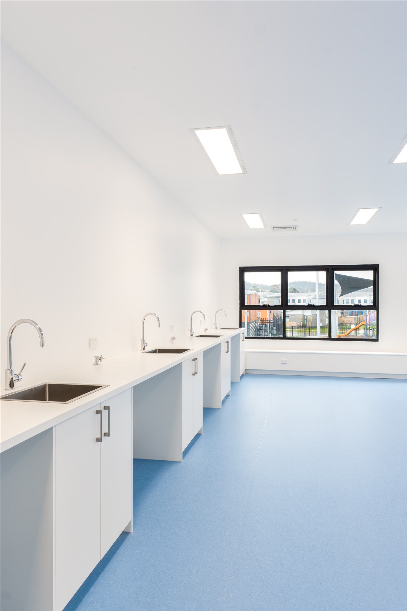 A Row of Sinks in a Room With Blue Floors and White Cabinets — Moltus Construction in Braddon,  ACT