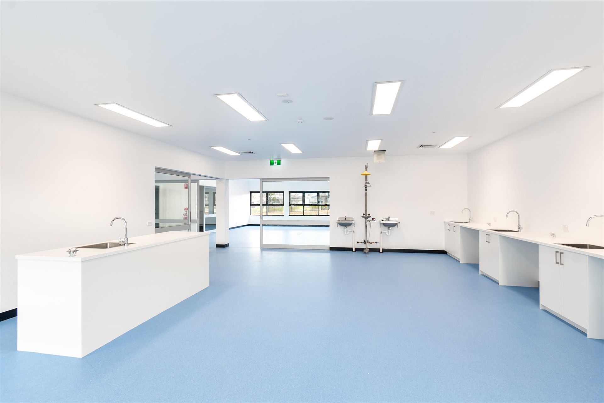 A Large Empty Room With Blue Floors and White Walls — Moltus Construction in Braddon,  ACT