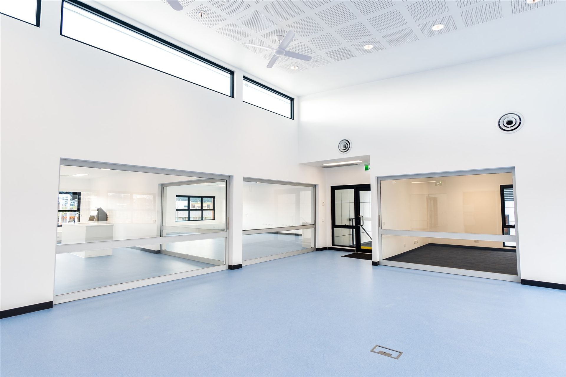 A Large Empty Room With a Blue Floor and White Walls — Moltus Construction in Braddon,  ACT