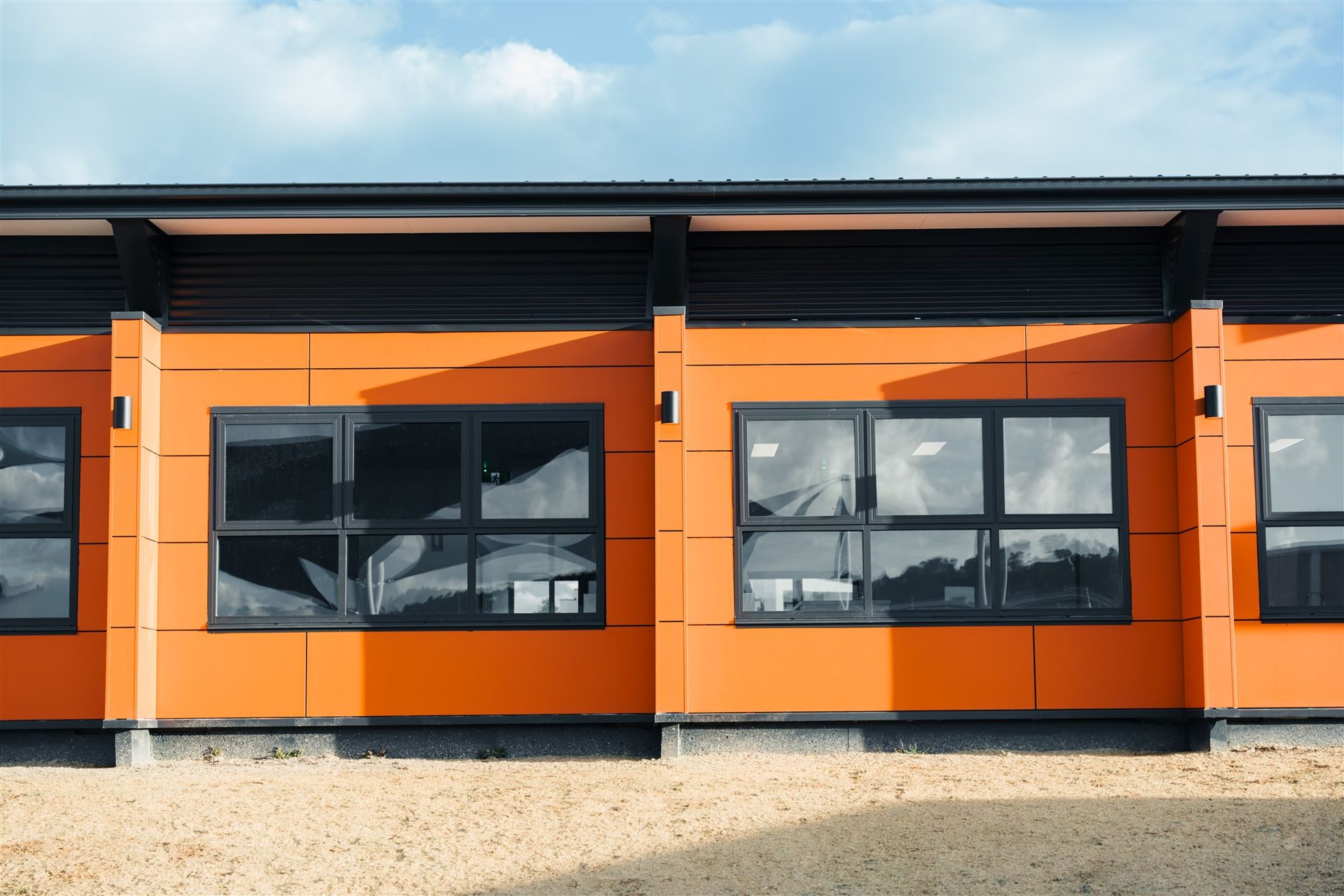 A Row of Orange Buildings With Black Windows Against a Blue Sky — Moltus Construction in Braddon,  ACT