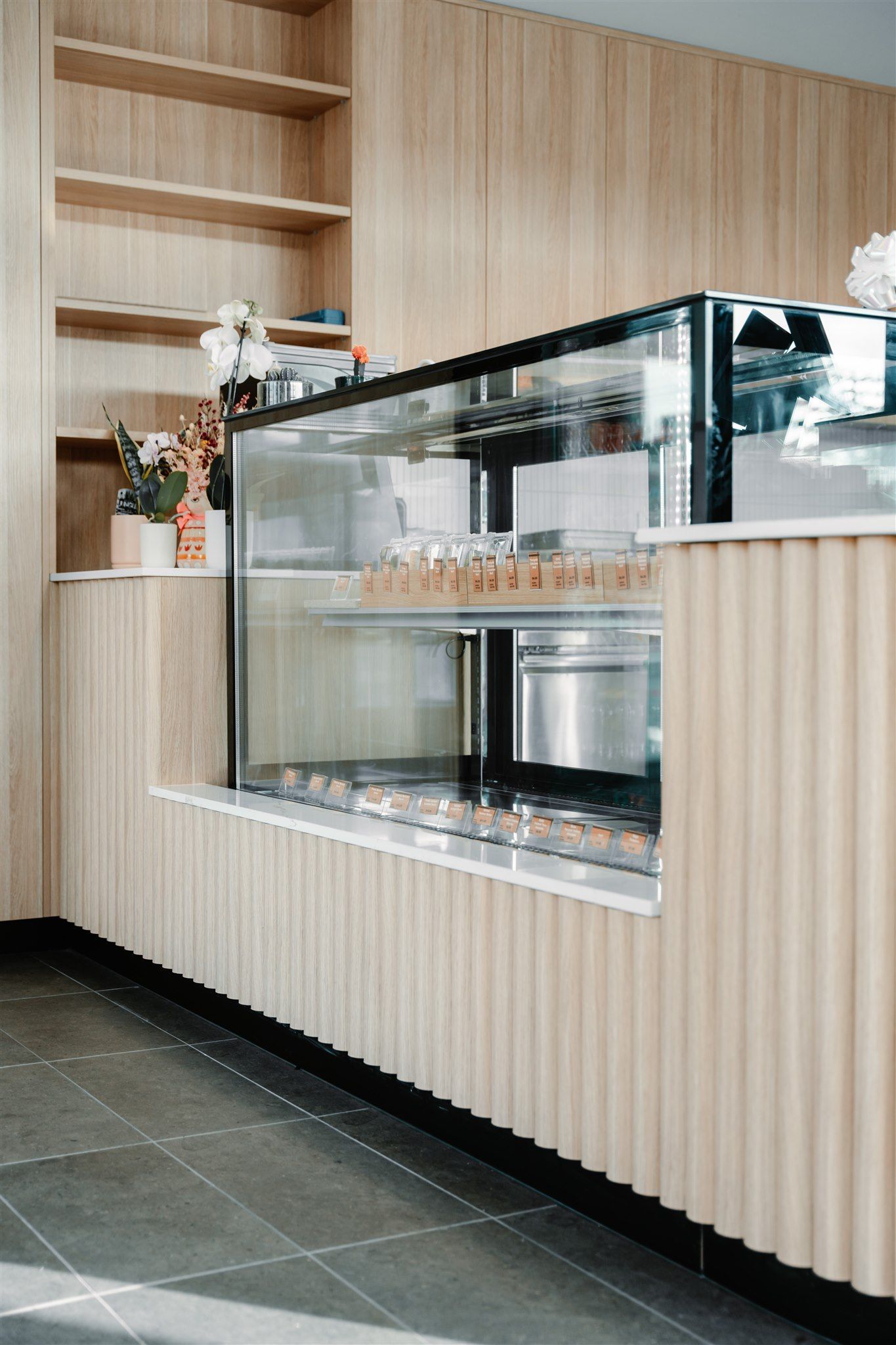 A Bakery With a Glass Display Case and a Wooden Counter — Moltus Construction in Braddon,  ACT