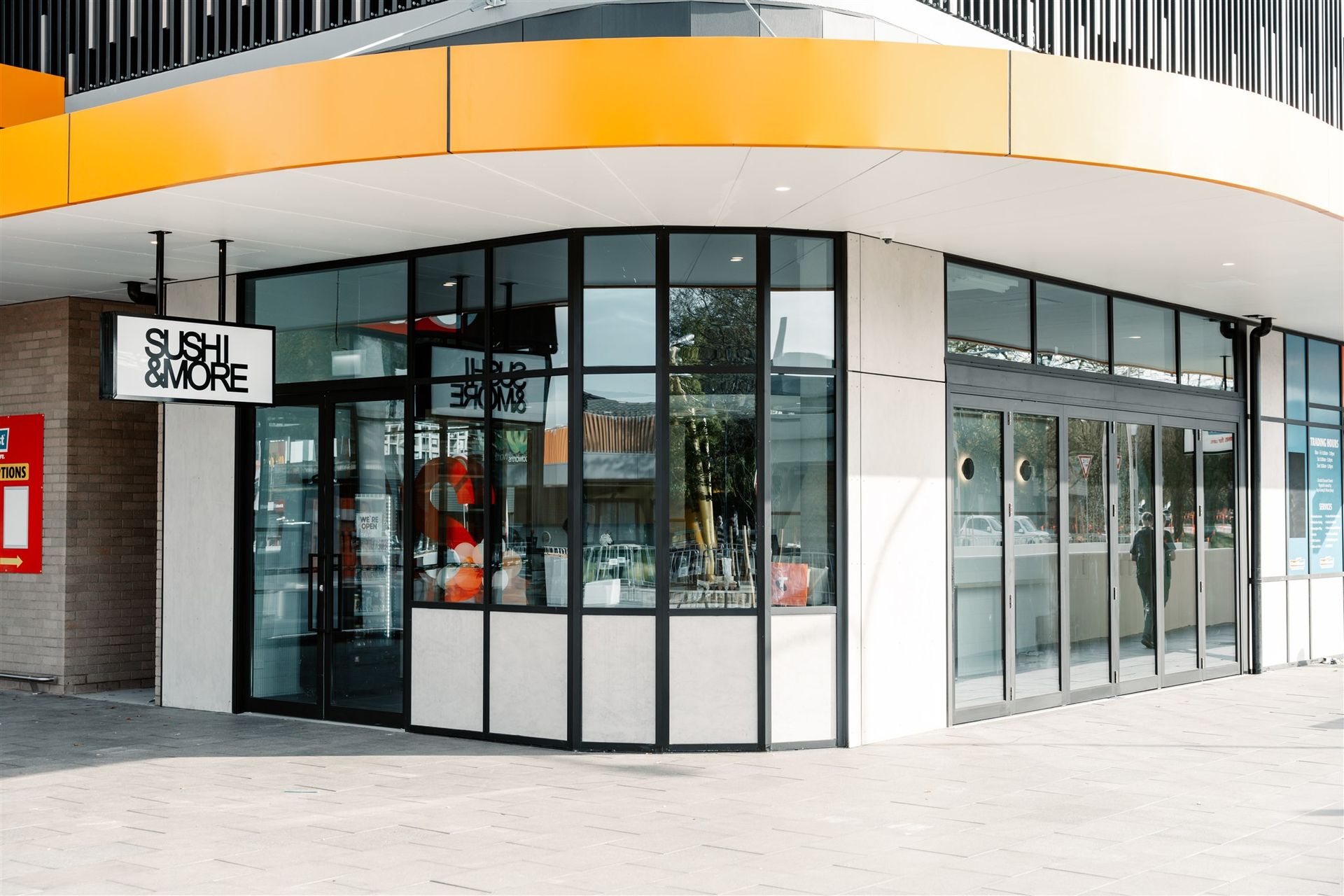 A Large Building With a Lot of Windows and a Sign That Says Sushi & More — Moltus Construction in Braddon,  ACT