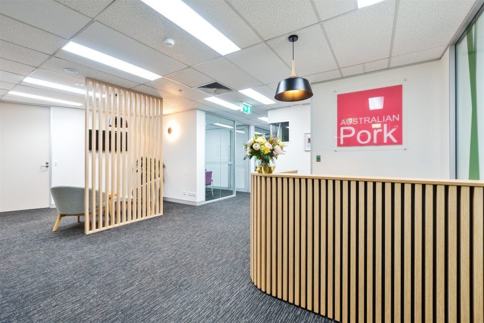 A Reception Area With a Wooden Counter and a Sign on the Wall — Moltus Construction in Braddon, ACT