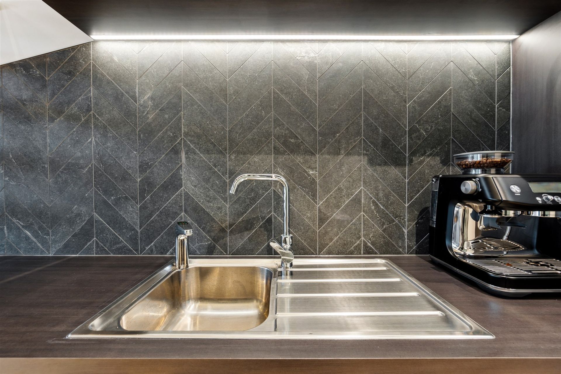 A Kitchen Sink With a Faucet and a Coffee Maker on the Counter — Moltus Construction in Braddon, ACT