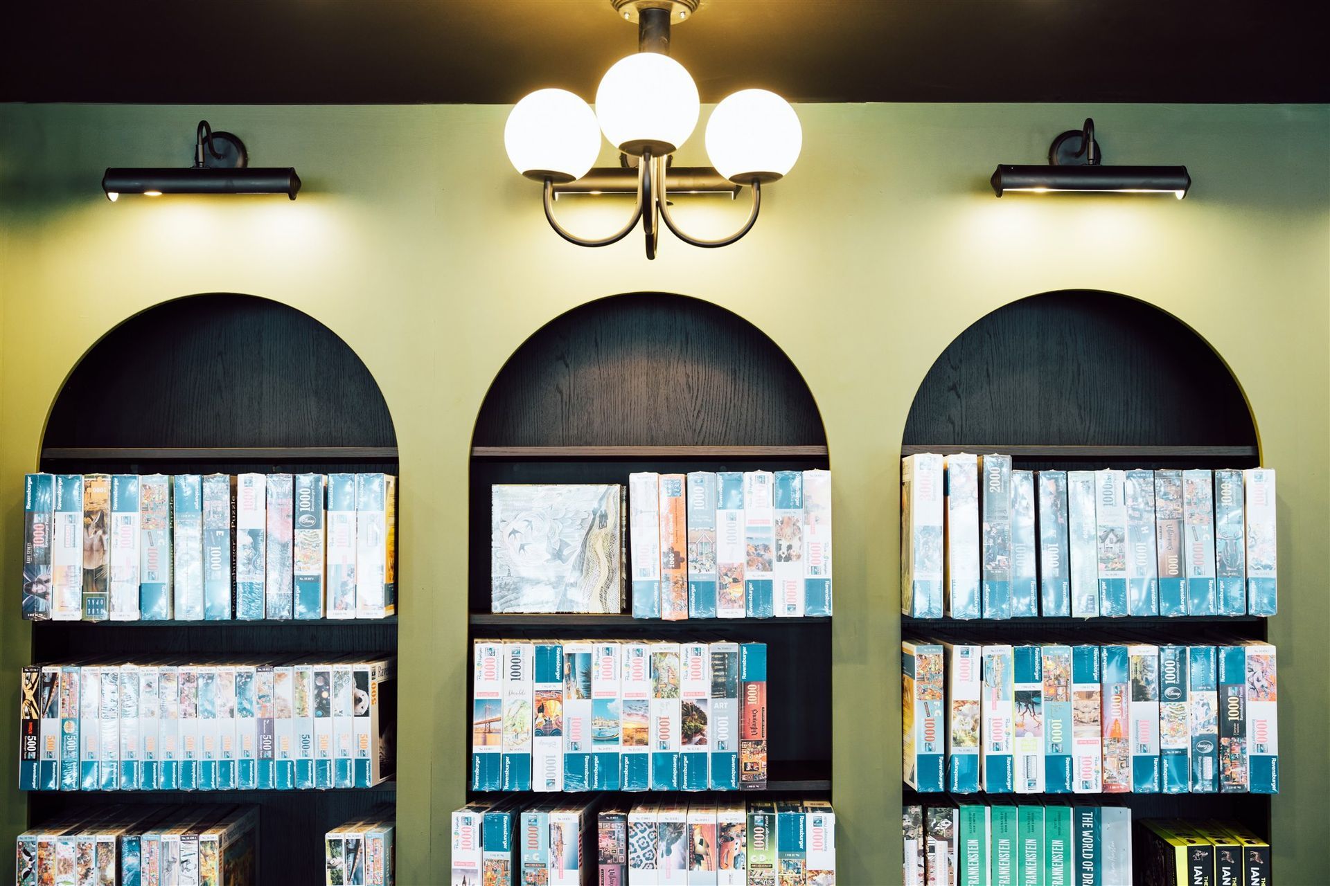 A Row of Shelves Filled With Books and a Chandelier Hanging From the Ceiling — Moltus Construction in Braddon, ACT