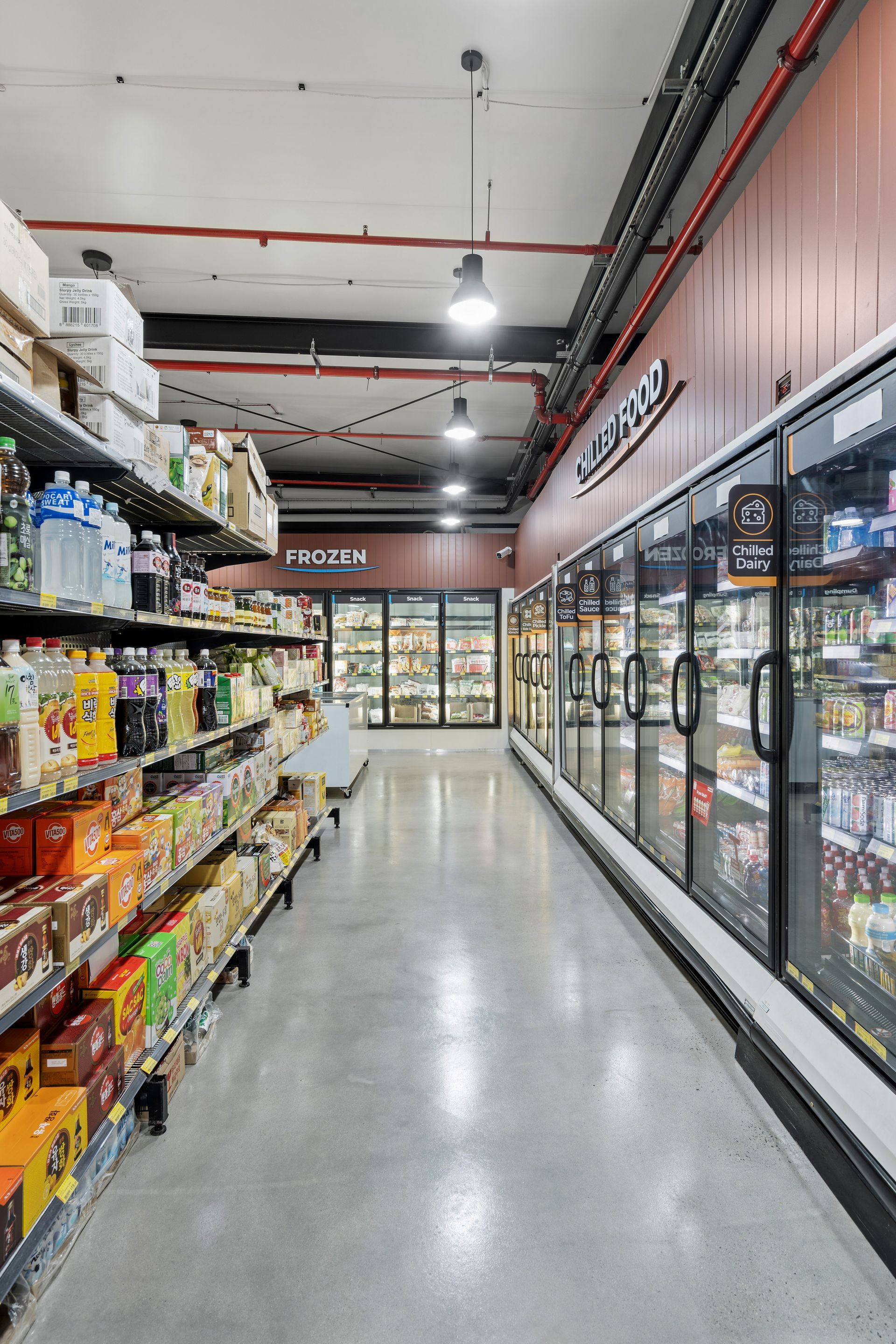 A Long Aisle of a Grocery Store With Lots of Shelves and Refrigerators — Moltus Construction in Braddon,  ACT