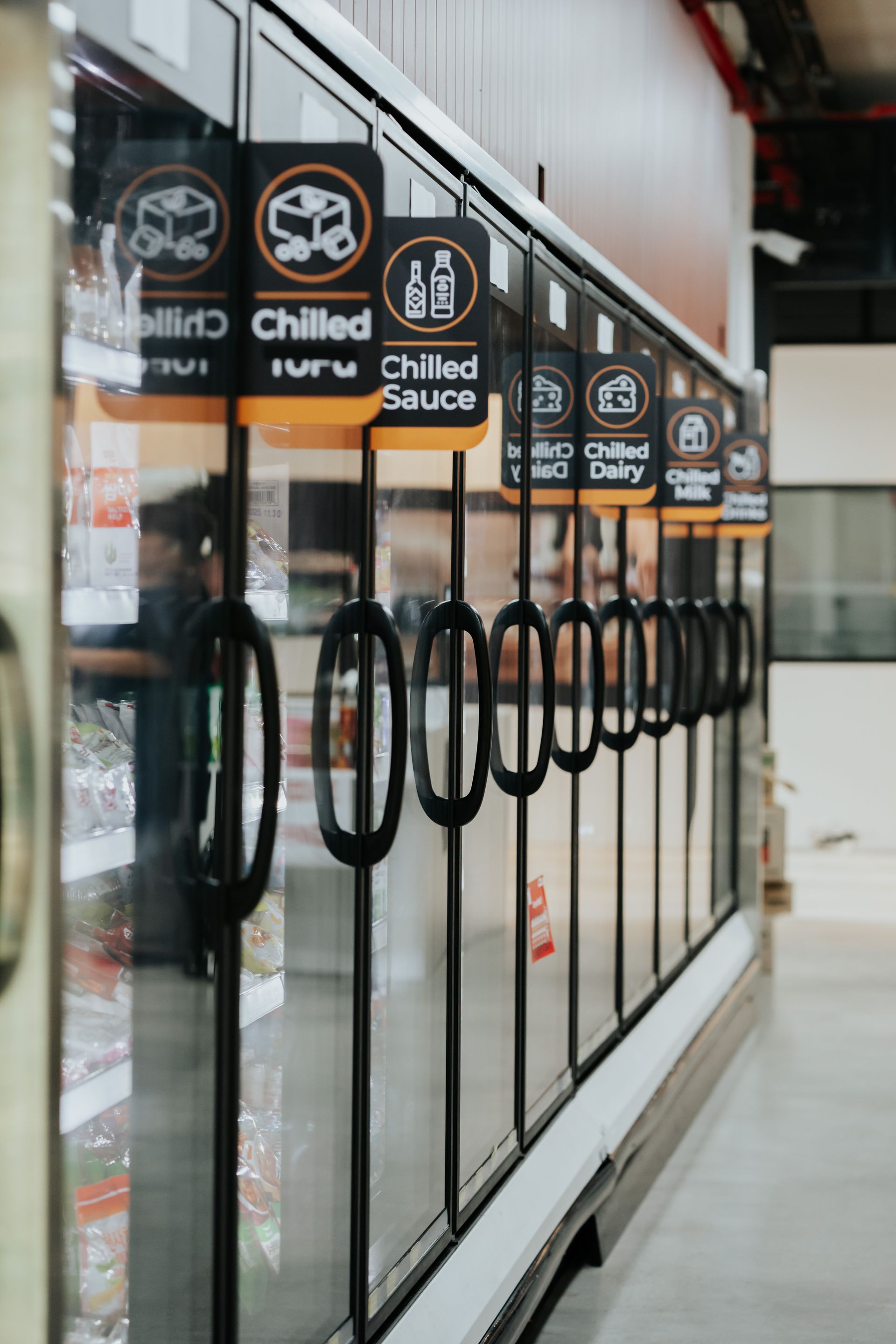 A Row of Glass Doors With Signs on Them That Say Chilled Sauce — Moltus Construction in Braddon,  ACT