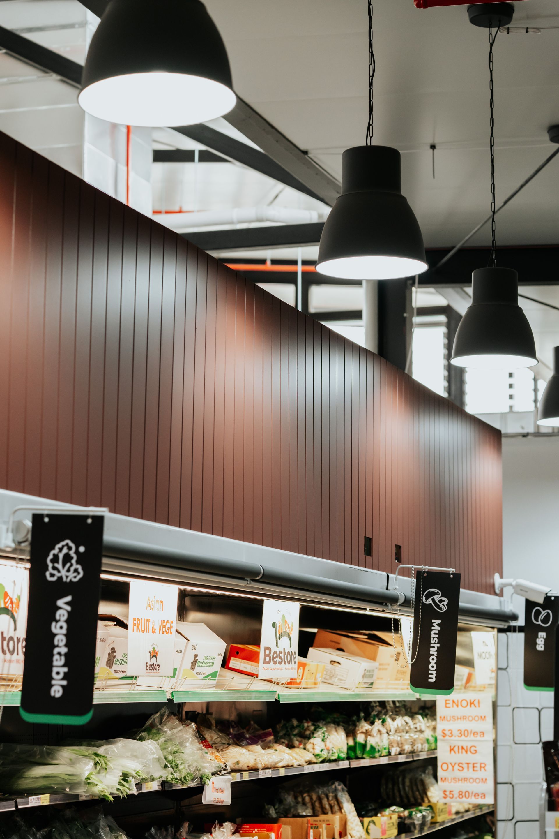 A Vegetable Section of a Grocery Store With Signs Hanging From the Ceiling — Moltus Construction in Braddon,  ACT
