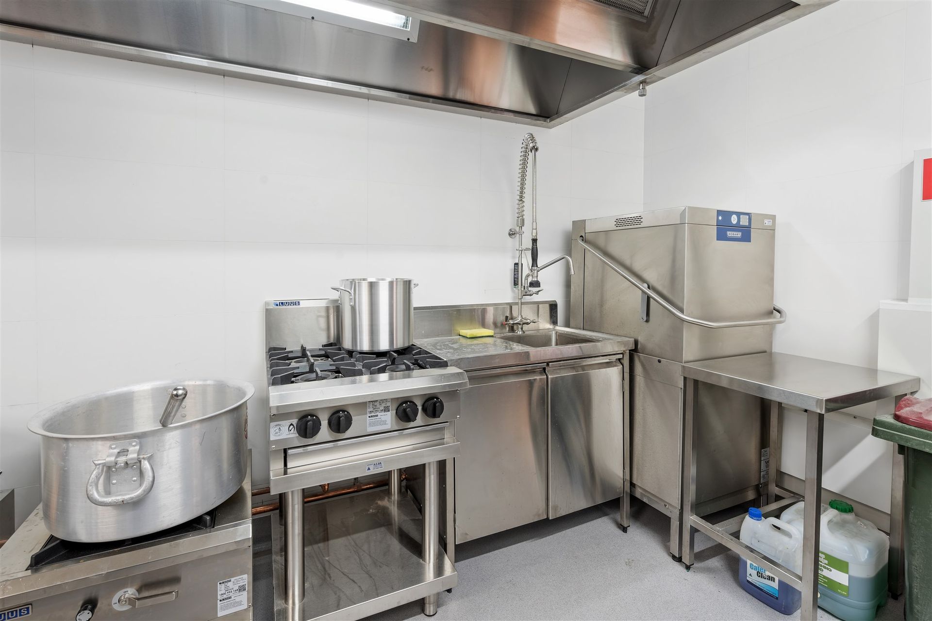 A Kitchen With Stainless Steel Appliances and Pots and Pans — Moltus Construction in Braddon,  ACT