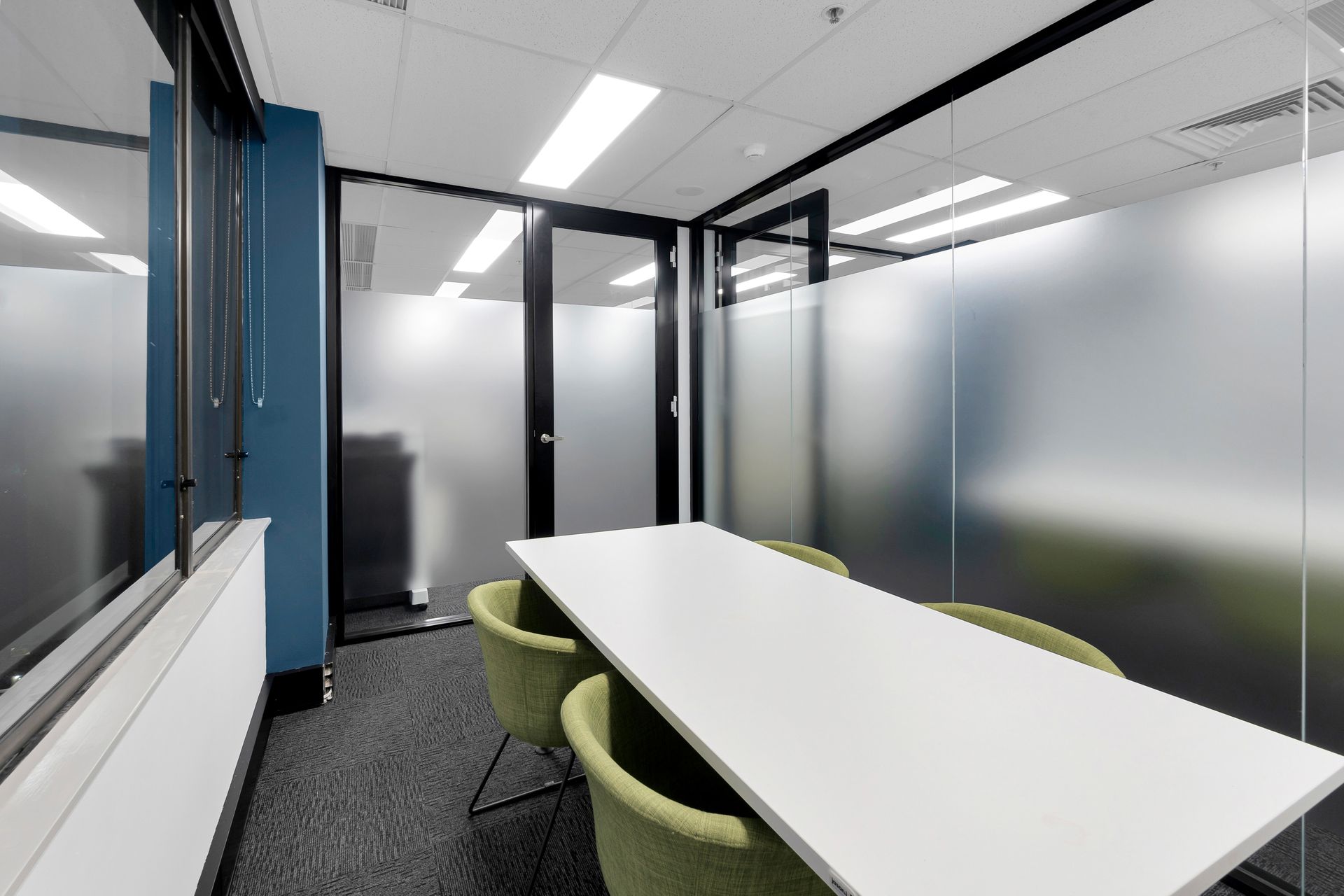 A Conference Room With a Long White Table and Green Chairs — Moltus Construction in Braddon,  ACT