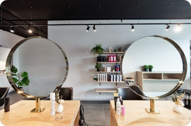 Two Round Mirrors Are Sitting on a Wooden Table in a Salon — Moltus Construction in Braddon,  ACT