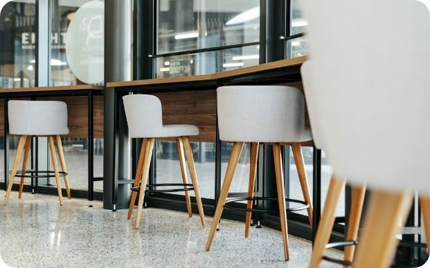 A Row of Bar Stools Are Lined Up in Front of a Window in a Restaurant — Moltus Construction in Braddon,  ACT