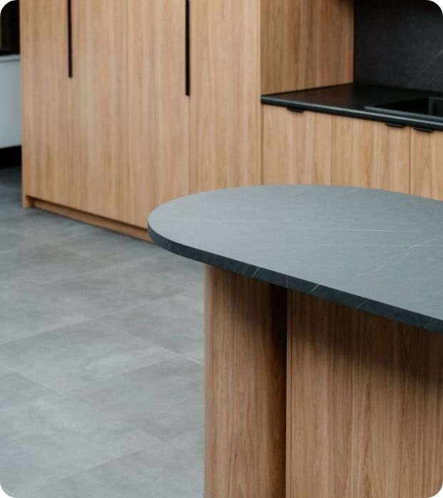 A Kitchen With Wooden Cabinets And A Black Counter Top  — Moltus Construction in Braddon, ACT