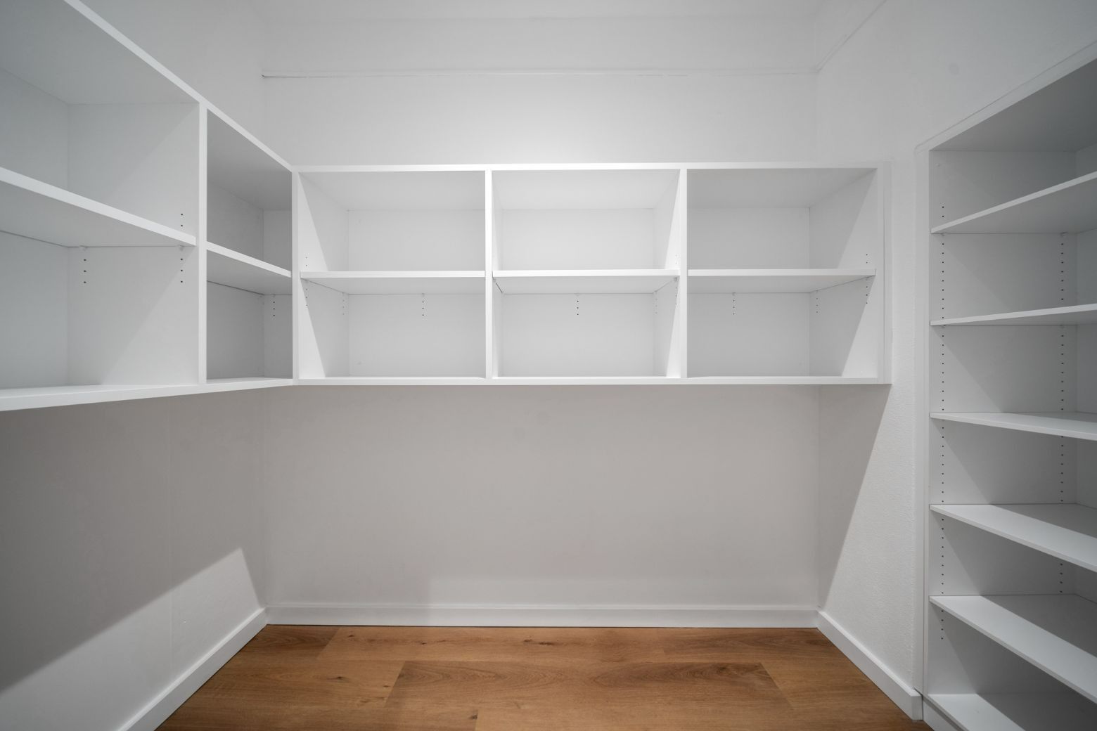 An Empty Walk in Closet With White Shelves and Wooden Floors — Moltus Construction in Braddon,  ACT
