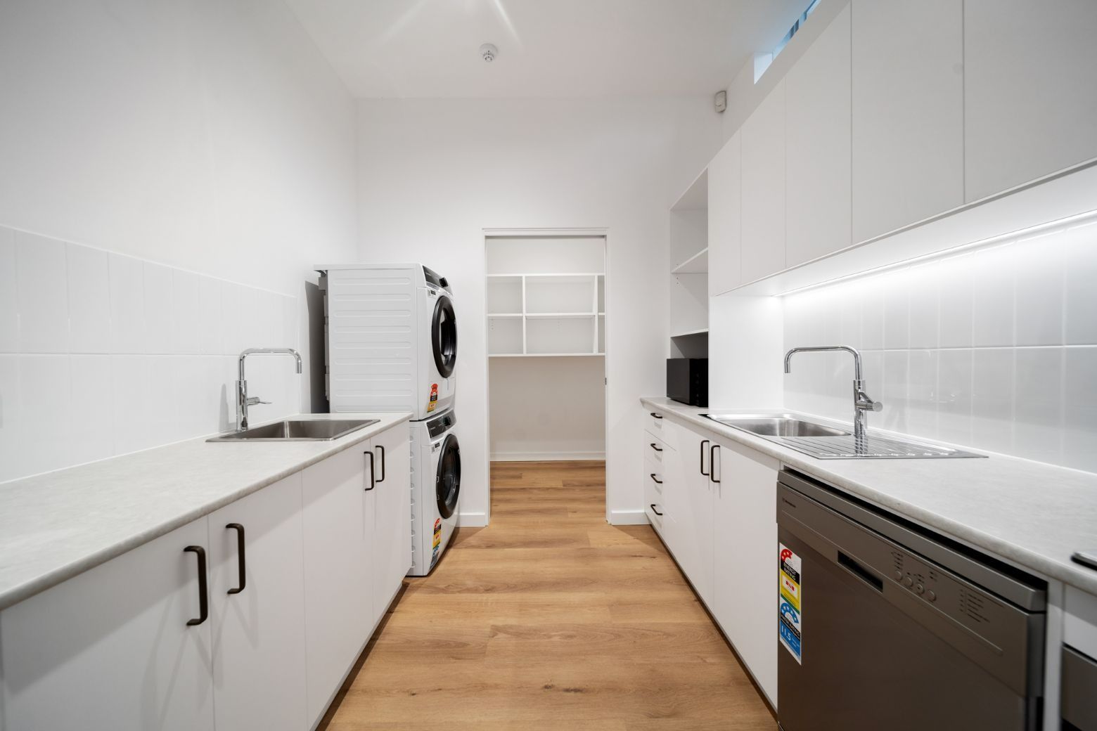 A Kitchen With White Cabinets, a Washer and Dryer, a Sink, and a Dishwasher — Moltus Construction in Braddon,  ACT
