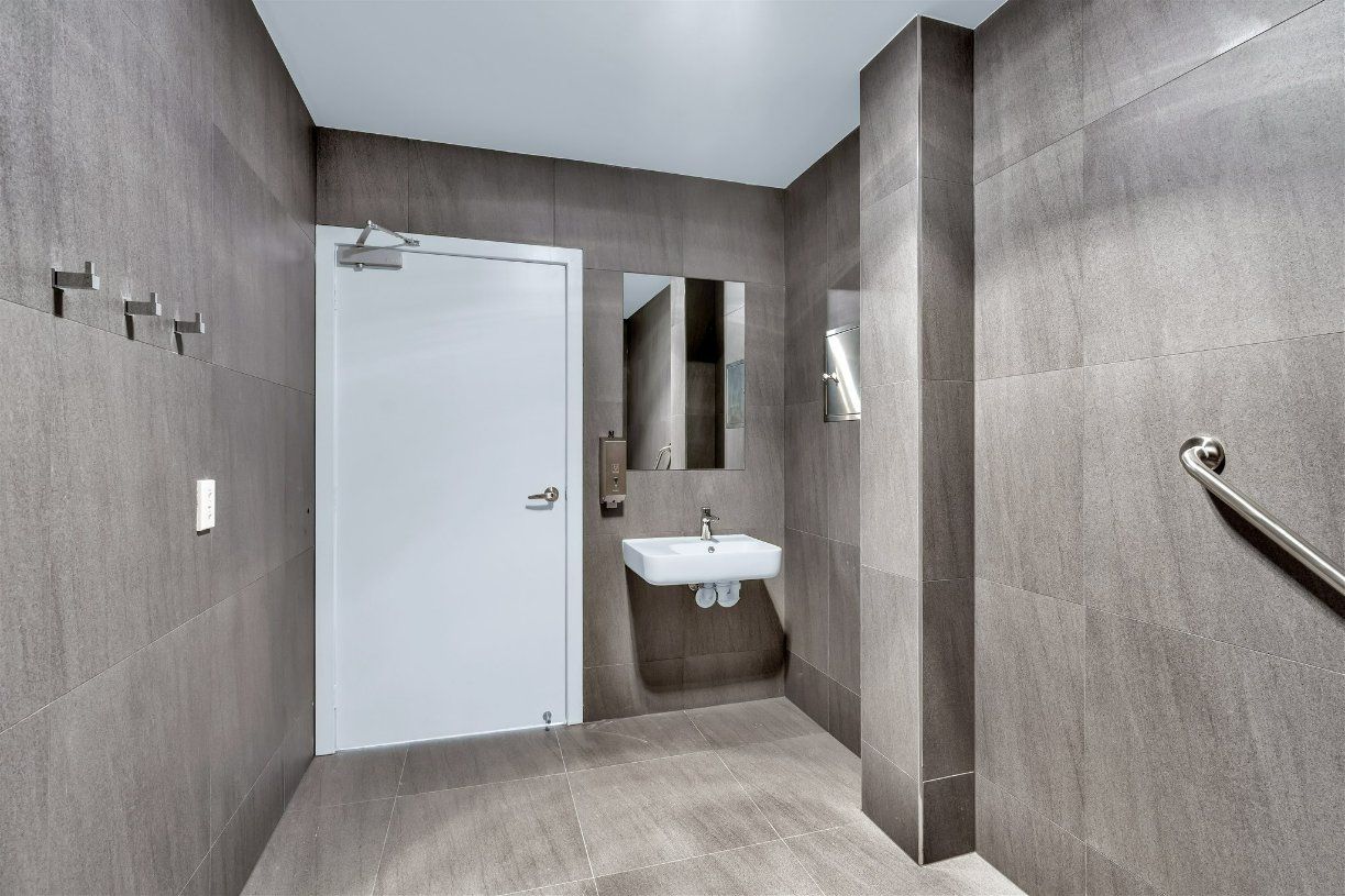A Bathroom With a Sink, Mirror and Door — Moltus Construction in Braddon,  ACT