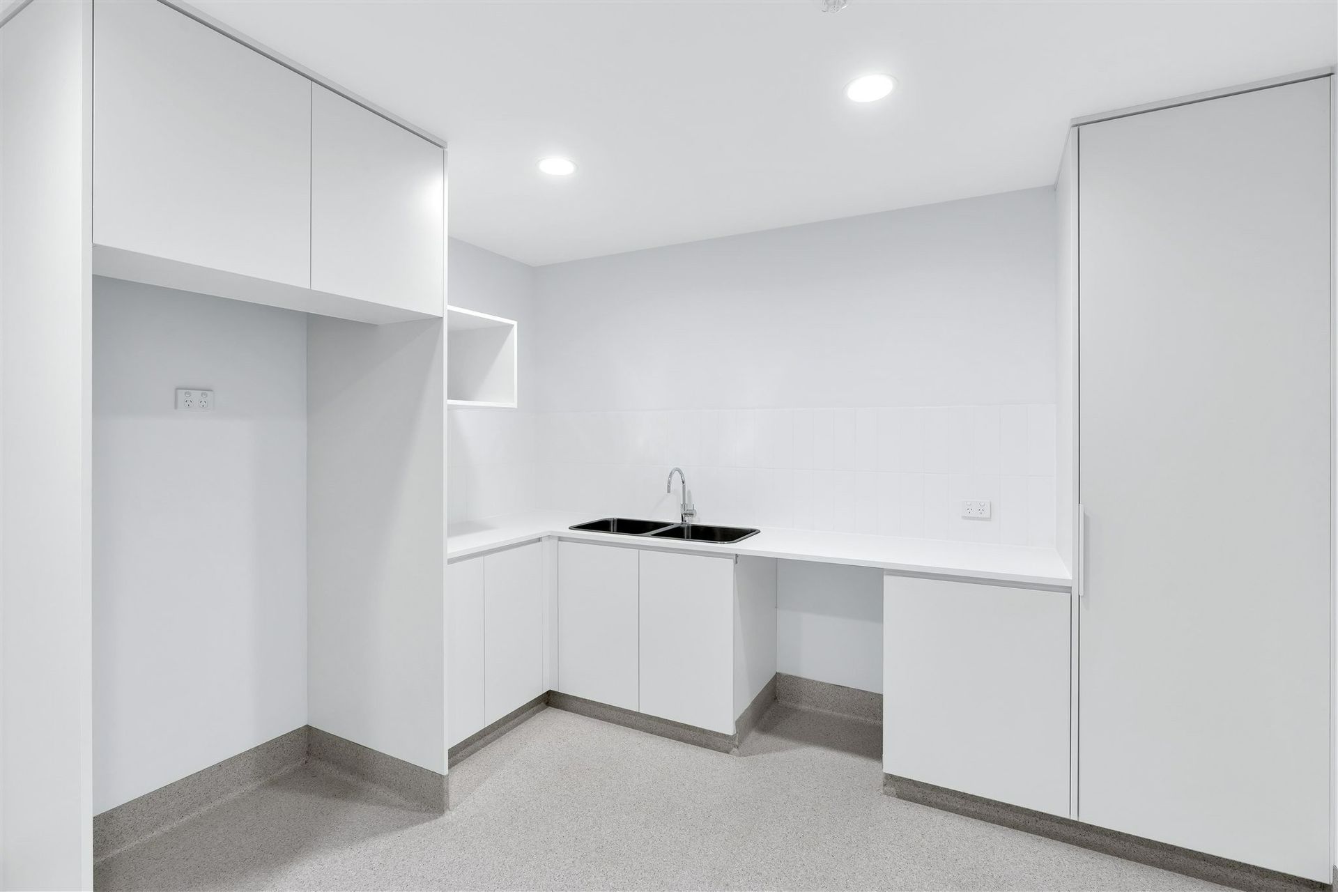 An Empty Kitchen With White Cabinets and a Sink — Moltus Construction in Braddon,  ACT