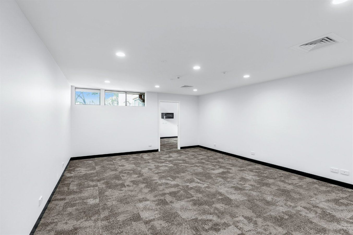 An Empty Room With a Carpeted Floor and White Walls — Moltus Construction in Braddon,  ACT