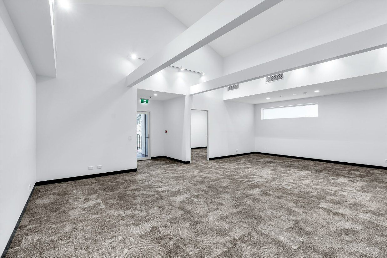 An Empty Room With a Carpeted Floor and White Walls — Moltus Construction in Braddon,  ACT