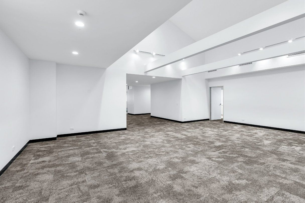 An Empty Basement With a Carpeted Floor and White Walls — Moltus Construction in Braddon,  ACT