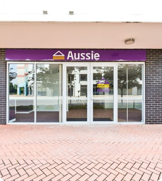 A Brick Building With a Purple Sign That Says Aussie — Moltus Construction in Braddon,  ACT