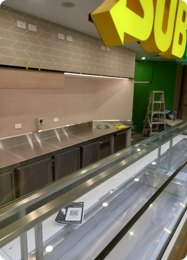 A Subway Restaurant is Being Built With Stainless Steel Counter Tops and a Glass Display Case — Moltus Construction in Braddon,  ACT