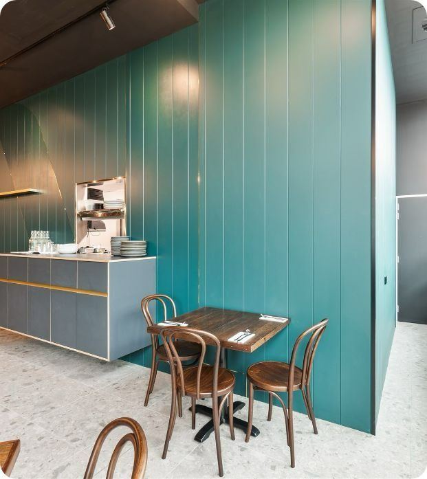 A Restaurant With a Table and Chairs in Front of a Blue Wall — Moltus Construction in Braddon,  ACT