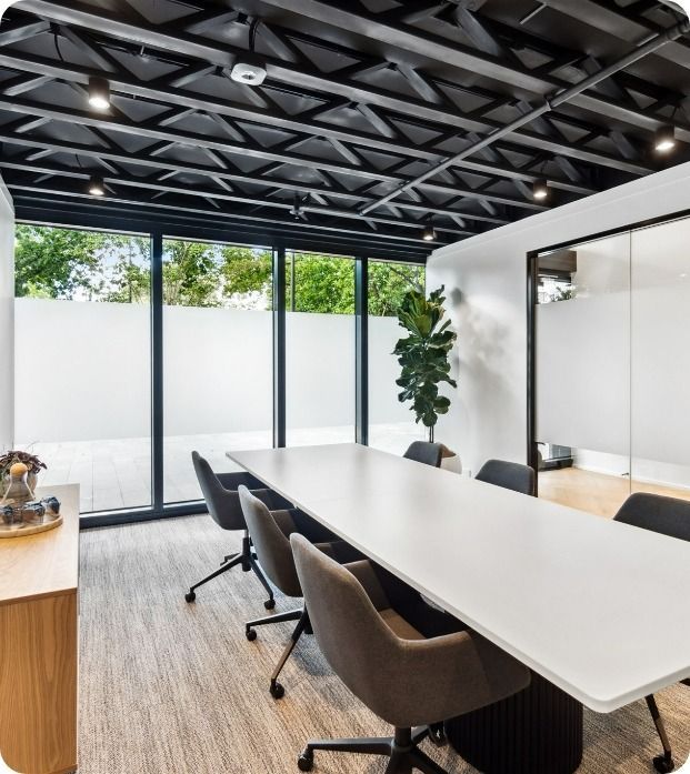 A Conference Room With A Table And Chairs And a plant— Moltus Construction in Braddon, ACT