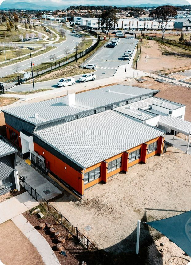 An Aerial View of a Large Building With a Gray Roof in a City — Moltus Construction in Braddon,  ACT