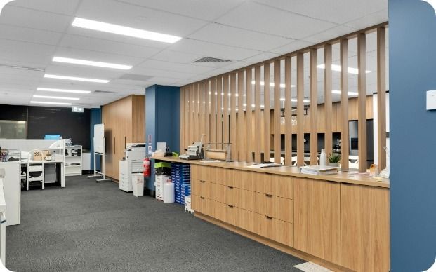 A Large Office With Wooden Cabinets and a Blue Wall — Moltus Construction in Braddon,  ACT