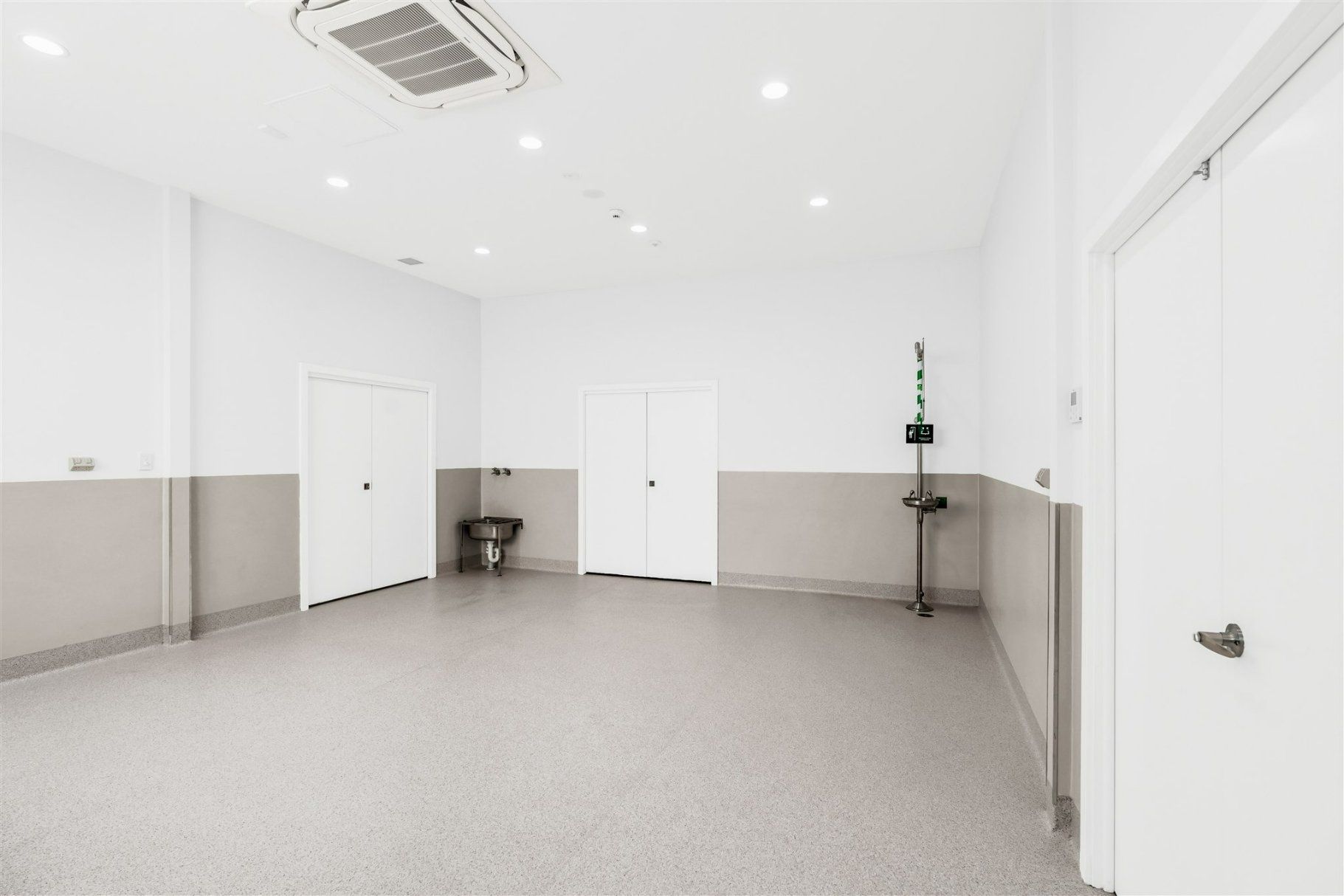 A Large Empty Room With White Walls and a Gray Floor — Moltus Construction in Braddon,  ACT