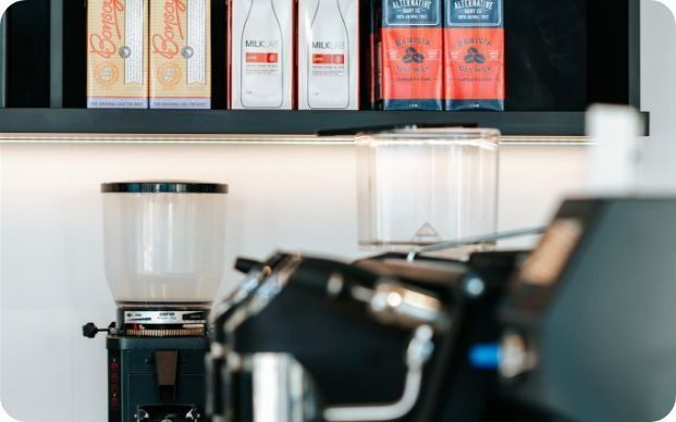 A Coffee Grinder is Sitting in Front of a Shelf With Boxes of Milk on It — Moltus Construction in Braddon,  ACT