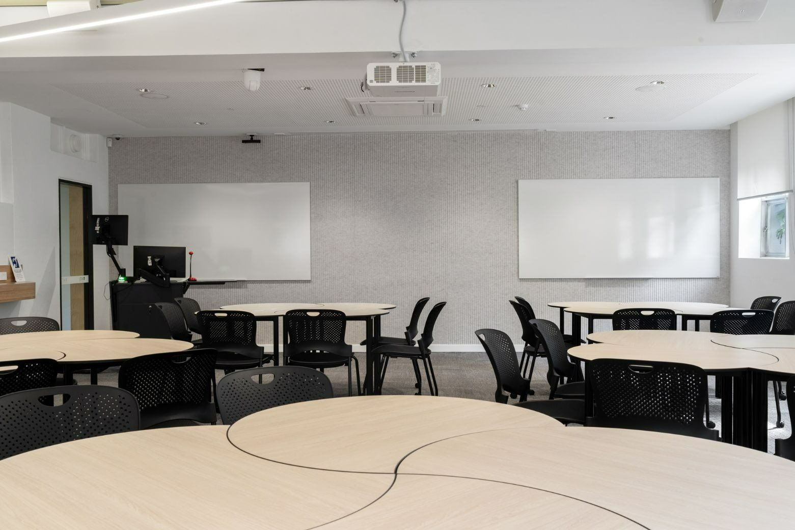 A Large Classroom With Tables and Chairs and a Projector — Moltus Construction in Braddon,  ACT