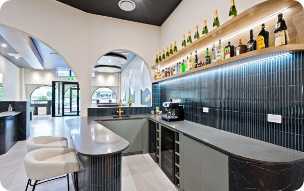 A Kitchen With a Bar and Shelves Filled With Bottles of Alcohol — Moltus Construction in Braddon,  ACT