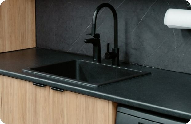 A Kitchen Sink With a Black Faucet and a Paper Towel Holder — Moltus Construction in Braddon,  ACT