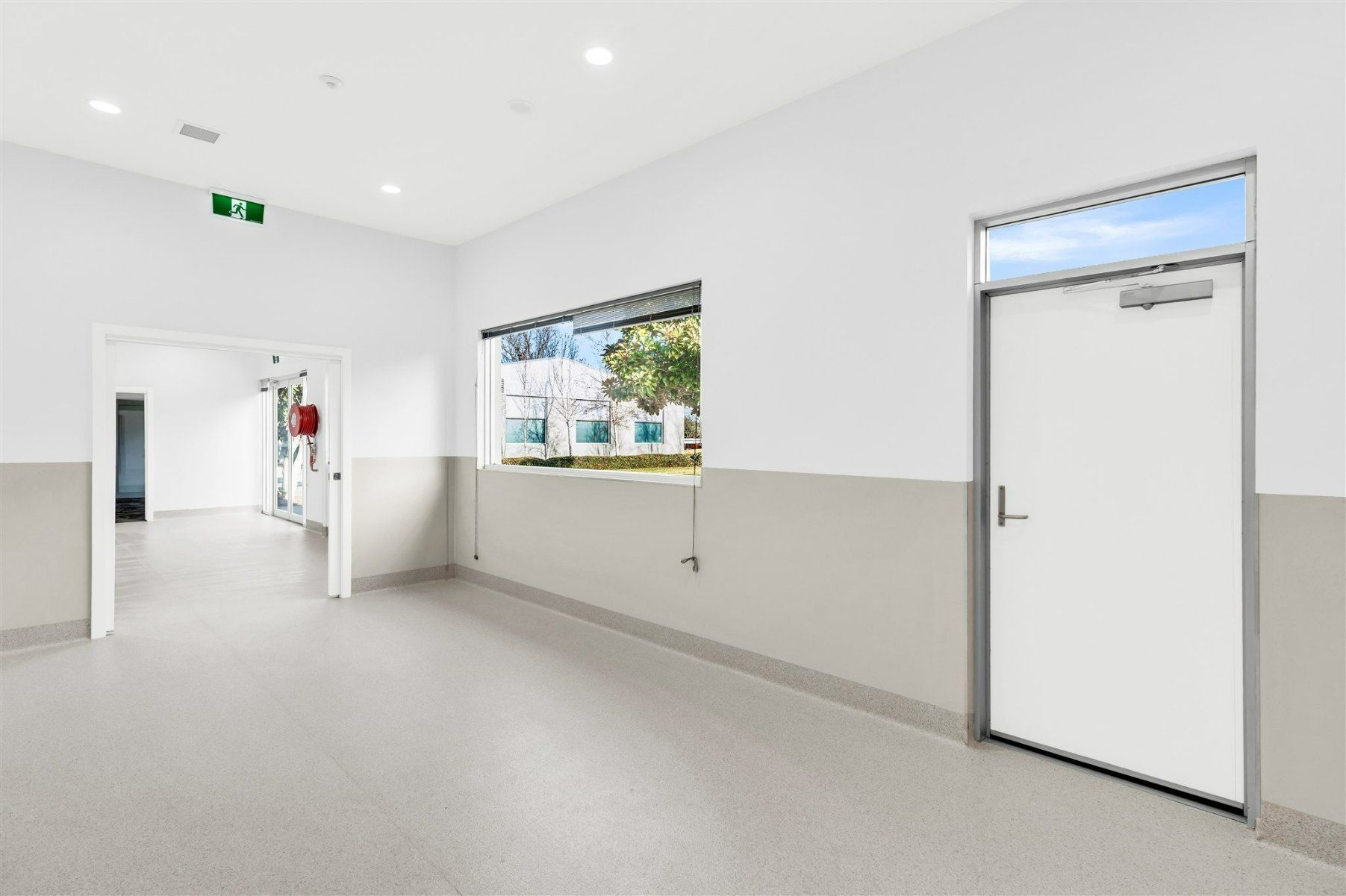 An Empty Hallway With a White Door and a Window — Moltus Construction in Braddon,  ACT