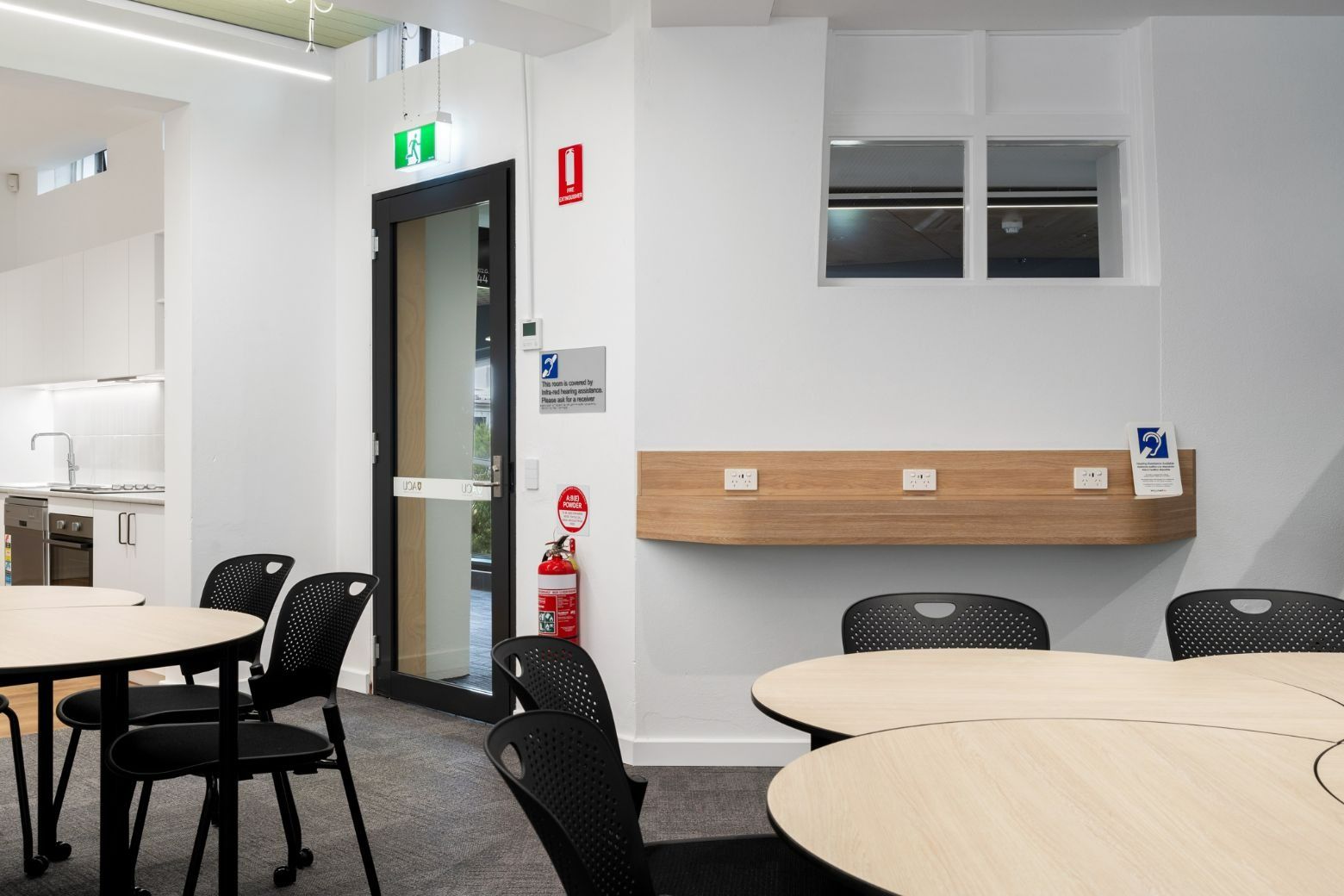 A Room With Tables and Chairs and a Fire Extinguisher on the Wall — Moltus Construction in Braddon,  ACT