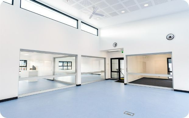 A Large Empty Room With a Blue Floor and White Walls — Moltus Construction in Braddon,  ACT