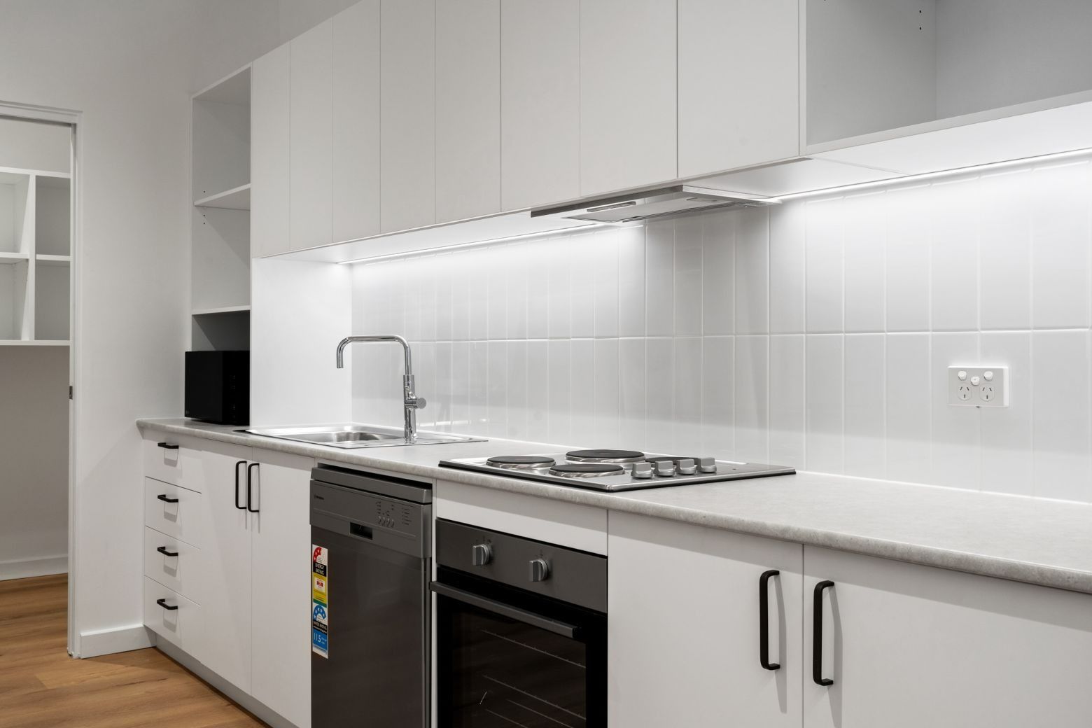 A Kitchen With White Cabinets, a Stove, a Dishwasher, and a Sink — Moltus Construction in Braddon,  ACT