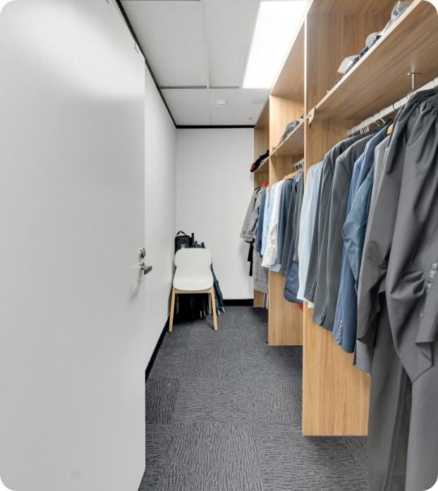A Walk in Closet Filled With Clothes and a Chair — Moltus Construction in Braddon,  ACT