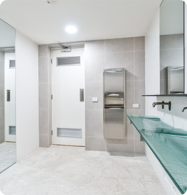 A Bathroom With Two Sinks and a Toilet Paper Dispenser — Moltus Construction in Braddon,  ACT