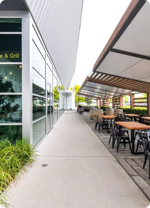A Long Walkway Leading to a Restaurant With Tables and Chairs — Moltus Construction in Braddon,  ACT