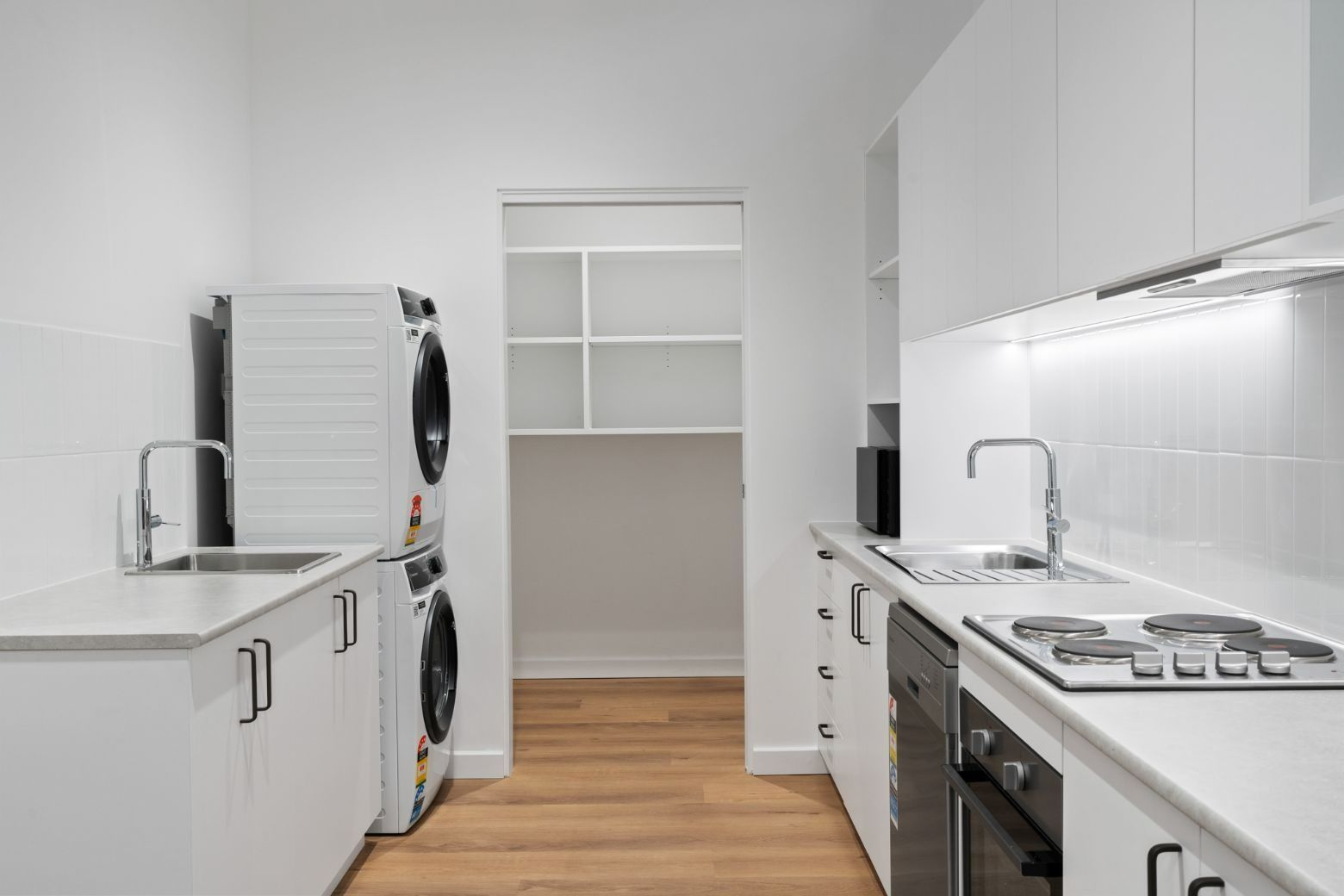 A Kitchen With White Cabinets, a Stove, a Sink and a Washer and Dryer — Moltus Construction in Braddon,  ACT