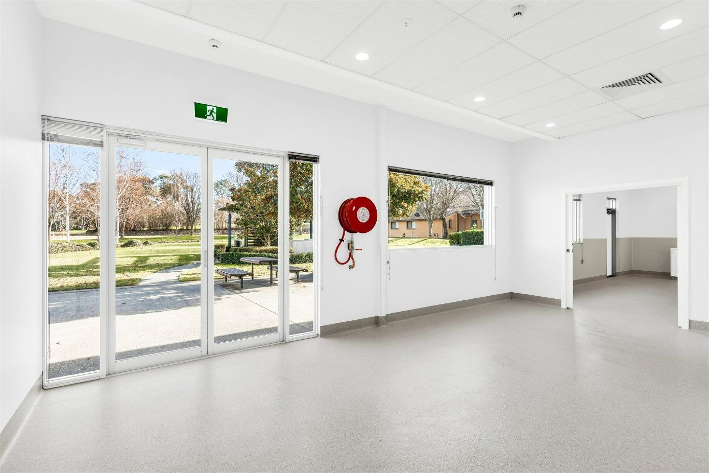 A Large Empty Room With Lots of Windows and a Fire Hose Hanging on the Wall — Moltus Construction in Braddon,  ACT